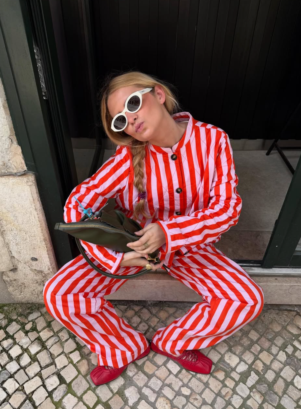 Person wearing a red and white striped outfit sitting on a bench.