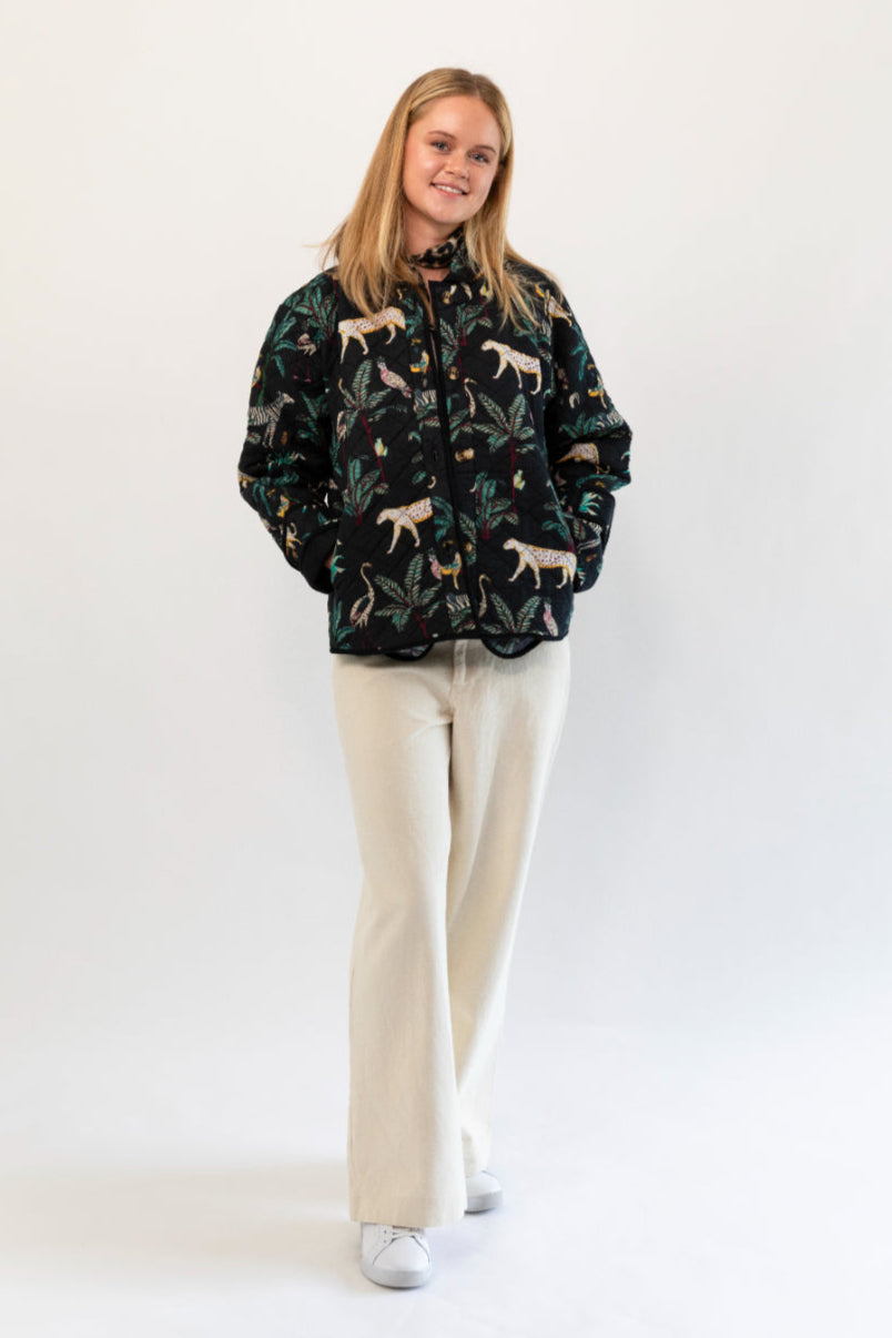 Person wearing a patterned jacket and beige pants on a white background