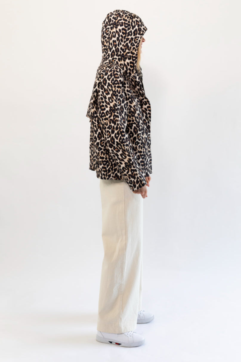 Person wearing a leopard print raincoat and beige pants on a white background
