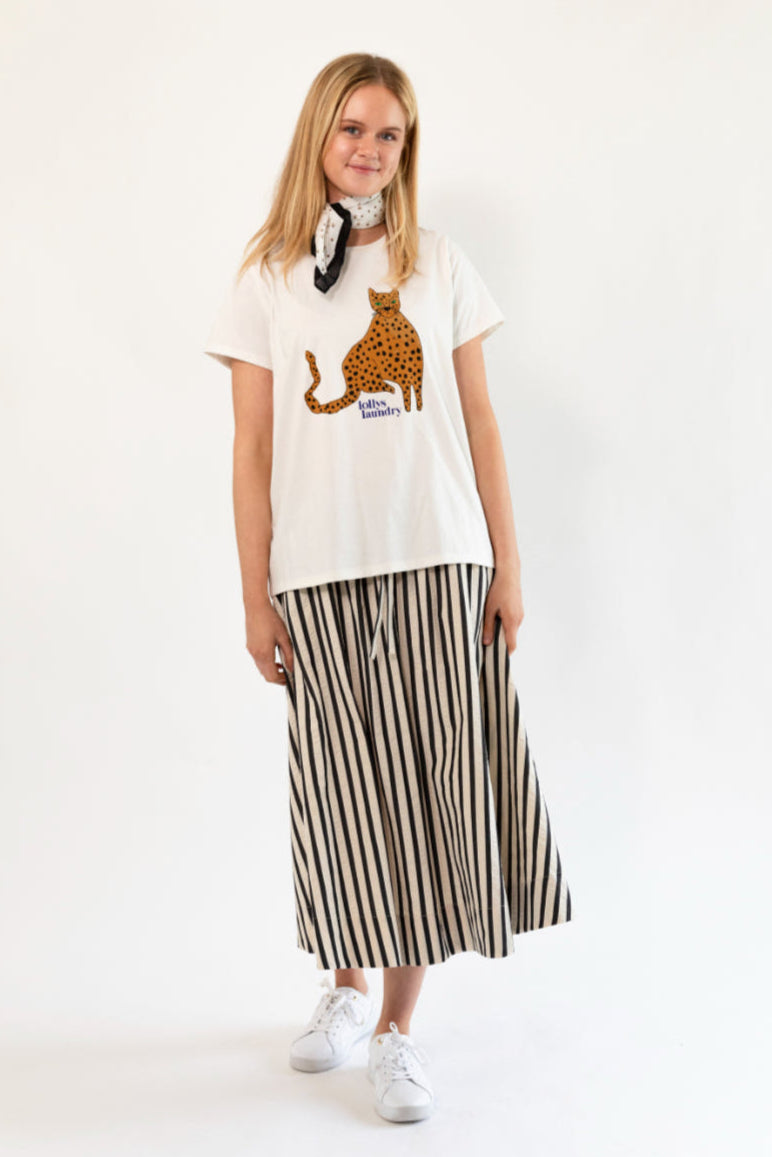 Woman wearing a white t-shirt with a graphic design and a striped skirt on a white background
