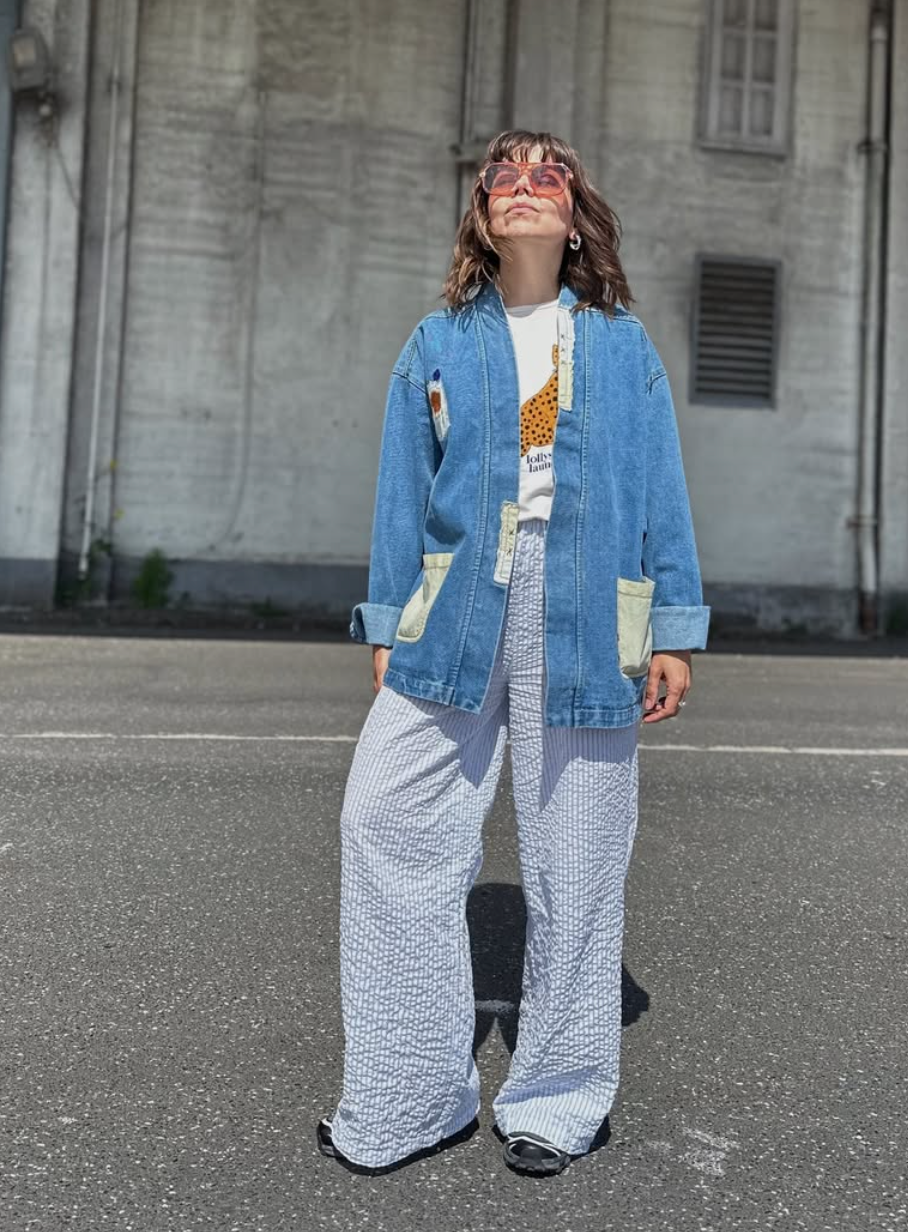 Person wearing a lollys laundry denim jacket and patterned pants standing on a street.