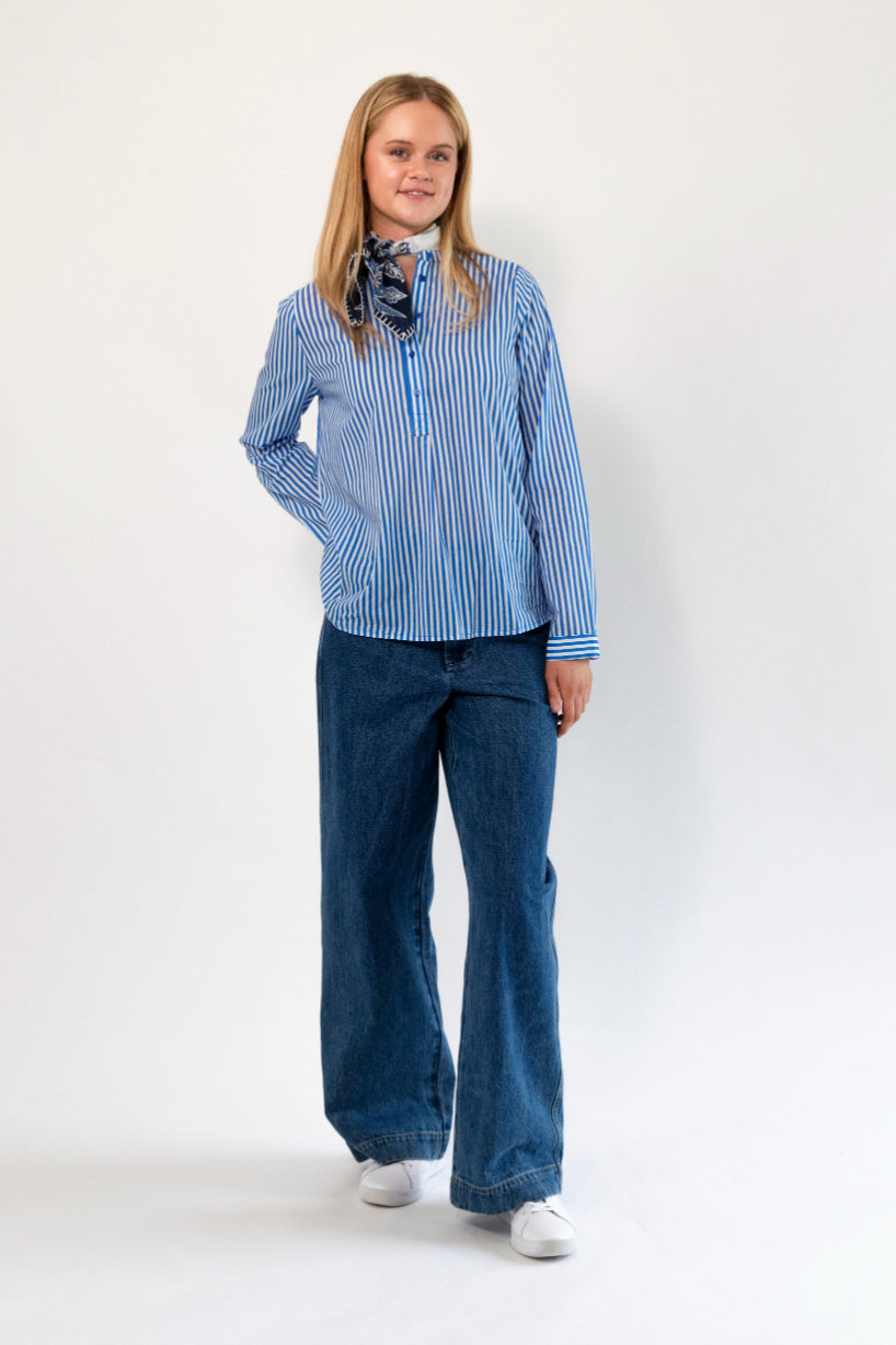Person wearing a blue striped shirt and jeans on a white background